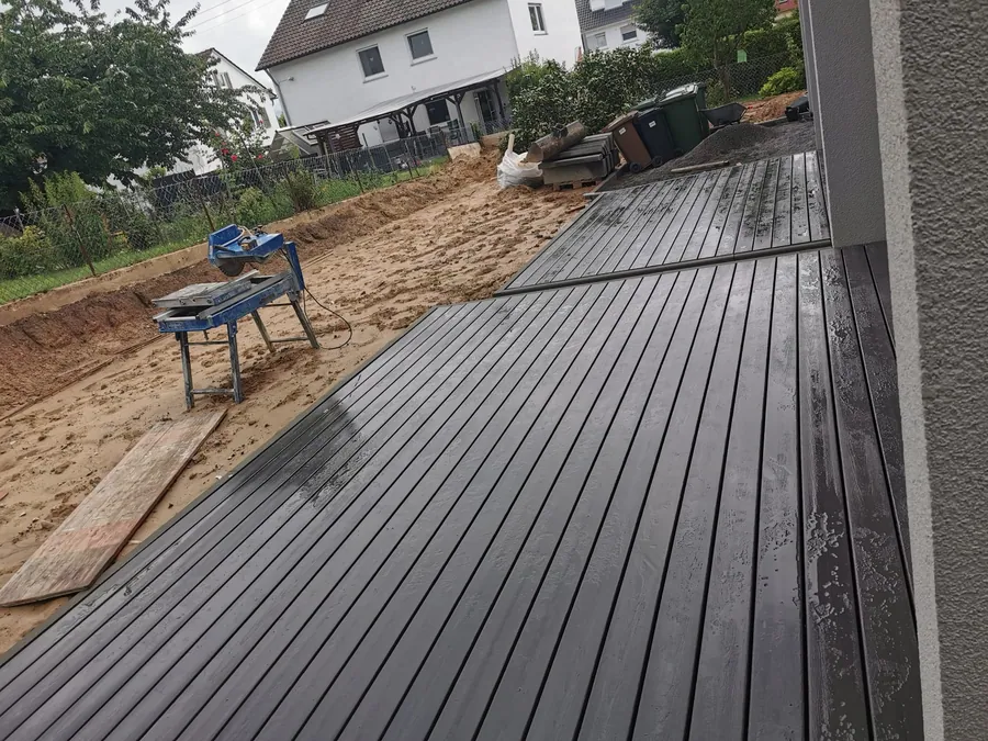 Frisch verlegte Terrassendielen, daneben der noch offene Erdbereich