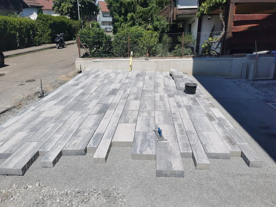 Großflächig verlegte Betonplatten einer Hofeinfahrt, Randsteine bereits gesetzt